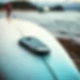 A close-up view of a surfboard equipped with a plastic nose guard highlighting its design features