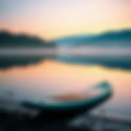 A serene lake at dawn with a stand-up paddleboard resting on the shore