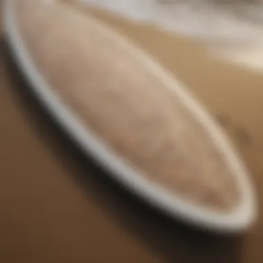 Close-up of a surfboard with intricate designs resting on the sand.